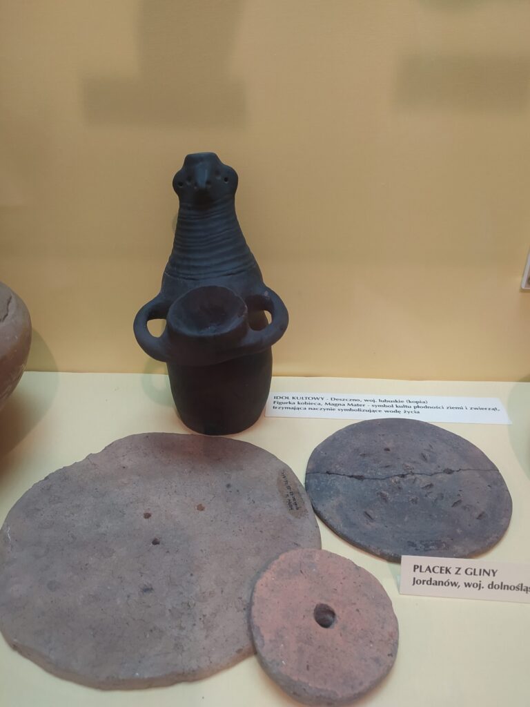 Naczynie i ceramiczne krążki na ekspozycji archeologicznej w Sobótce
